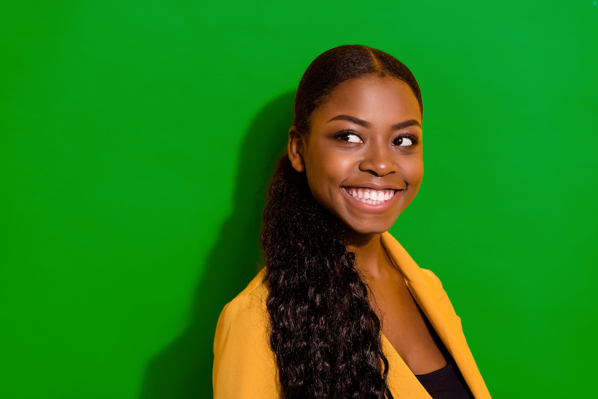 A woman in a yellow jacket looking off camera and smiling